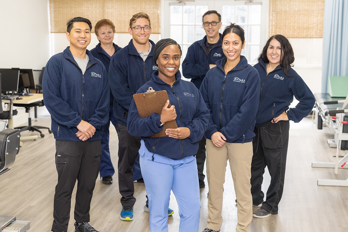 Several therapists and caregivers standing in the rehab gym of Aviara Healthcare