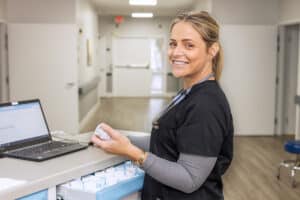 A caregiver at the nurses' cart in the hallway at Aviara Healthcare facility