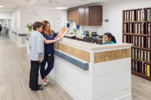 caregiver at the nurses' station in the hallway at Aviara Healthcare facility