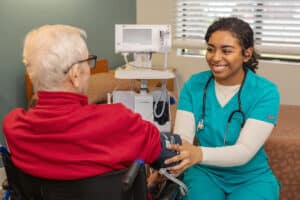 a caregiver taking the blood pressure of a resident at Aviara Healthcare