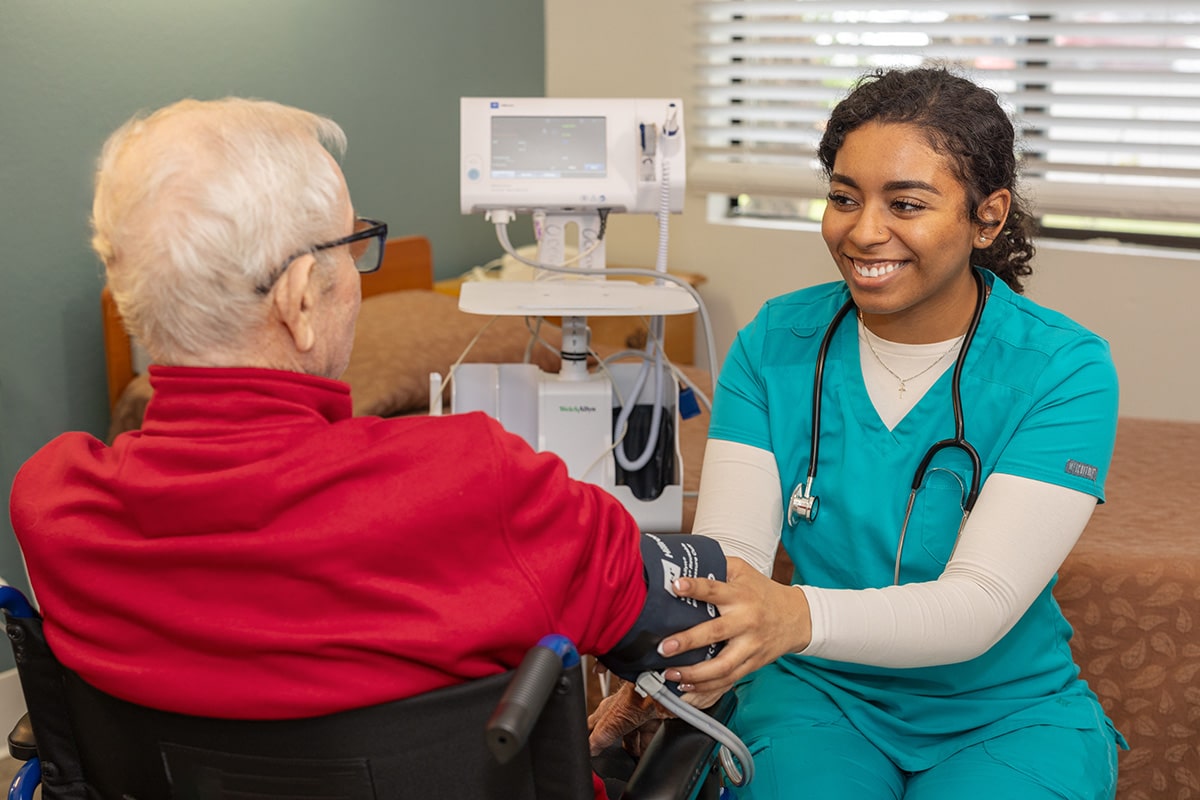 a caregiver taking the blood pressure of a resident at Aviara Healthcare