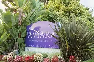 the monument sign in front of the Aviara Healthcare facility with green plants and flowers